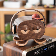 Handcrafted  octopus jewelry box with headphones and red cap, made of walnut ,sitting on a speaker in a cozy modern room