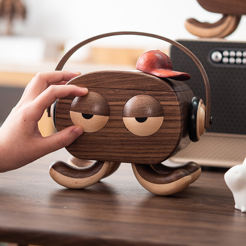 Person opening a cute wooden octopus jewelry box with headphones and red cap, showing smooth walnut wood craftsmanship